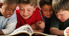 photo of four boys looking at a book
